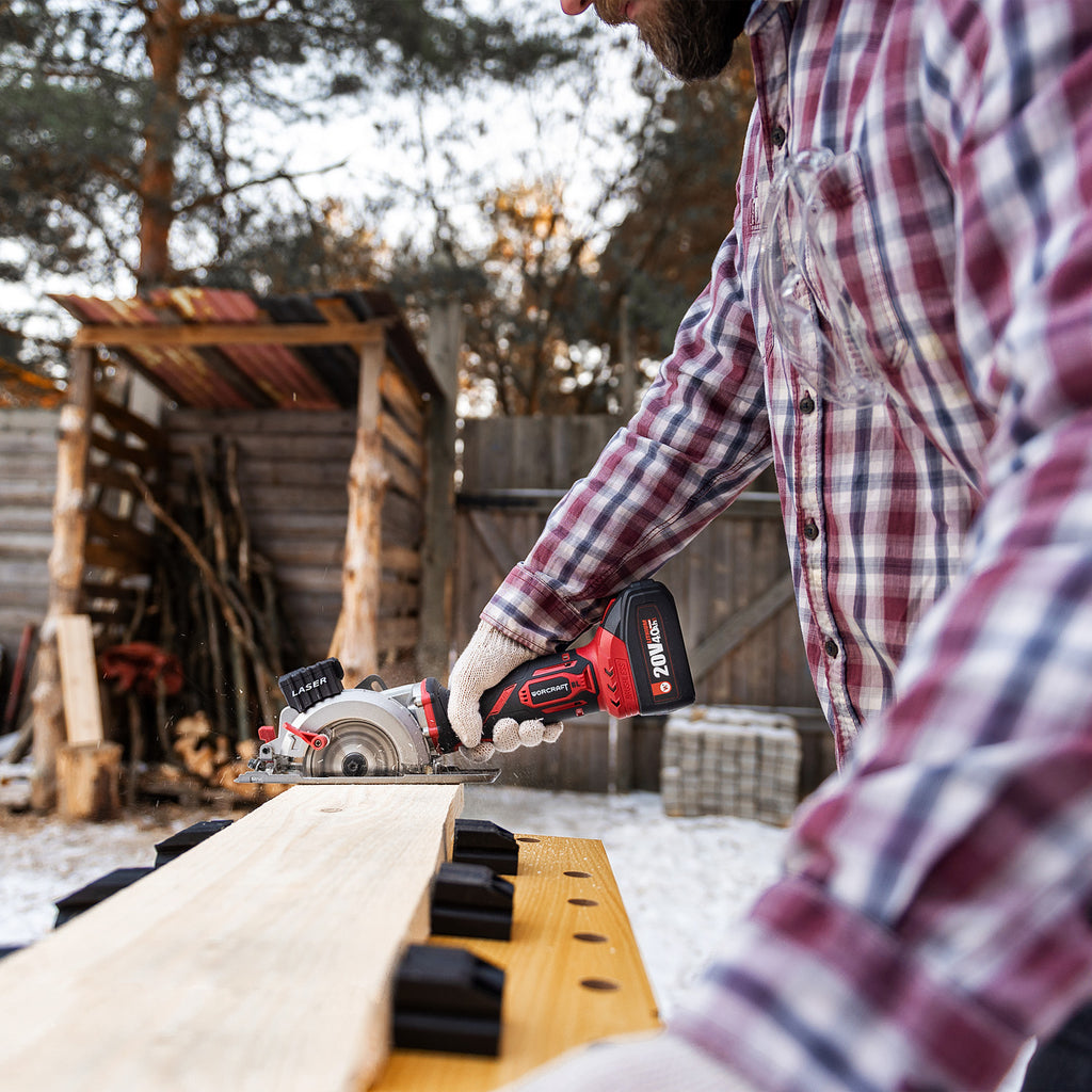 Man cutting wooden board with Worcraft mini circular saw outside