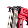 A close-up of a Worcraft red and black cordless nailer with a silver metal gauge and warning label, shown on a clean white background.