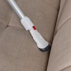 A worcraft cordless vacuum stick with brush attachment cleaning a couch