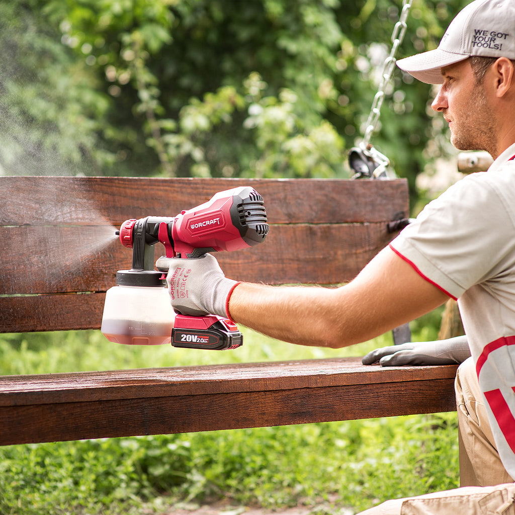 Man spraying paint on a bench using a Worcraft paint sprayer