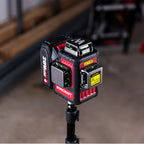 A WORCRAFT 20V MAX laser level mounted on a tripod stand in a workshop setting.