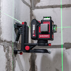 A red and black WORCRAFT 20V MAX 3-in-1 laser level mounted on a black clamp against an unfinished concrete wall, with green laser lines projected on the wall.